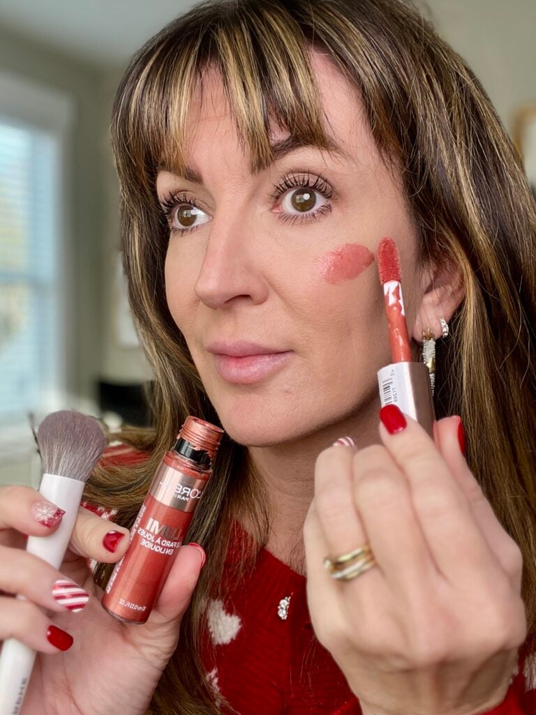 Woman holding L'Oreal Le Lumi liquid blush in Glowy True Rose with cream blush brush showing rosy cheek application