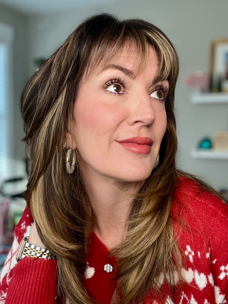 Side profile of completed simple makeup look with natural skin, soft brows, neutral eyes, rosy blush and glossy mauve lip