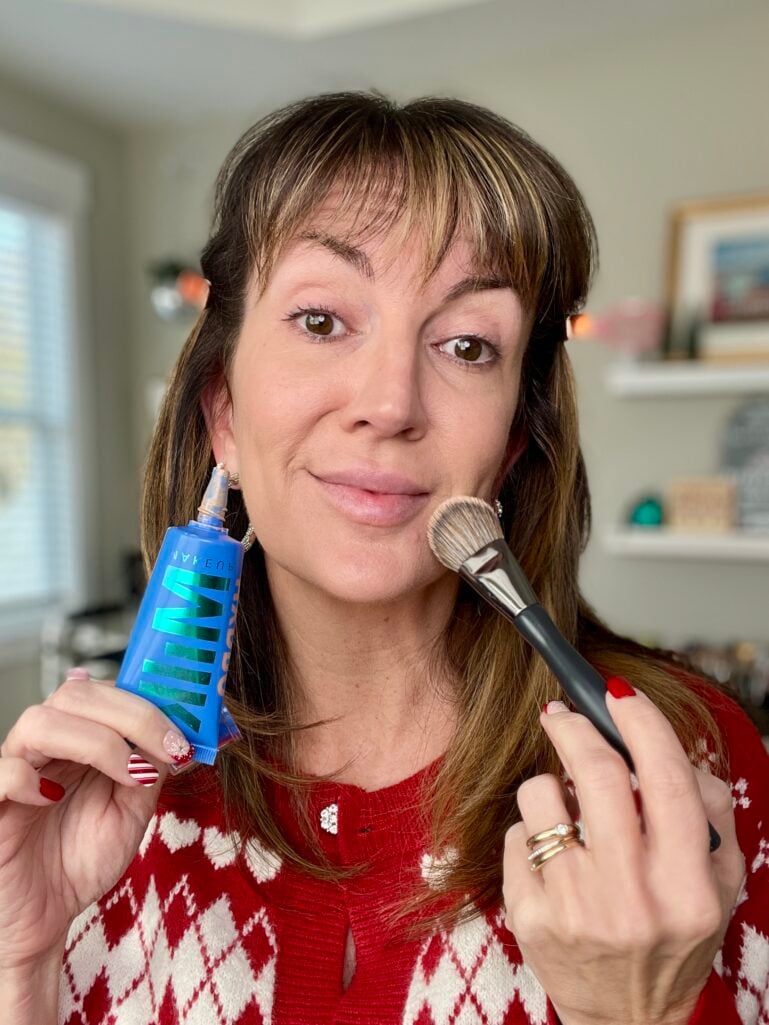 Woman holding Milk Makeup Hydro Grip gel tint and foundation brush with bare face ready to apply lightweight foundation