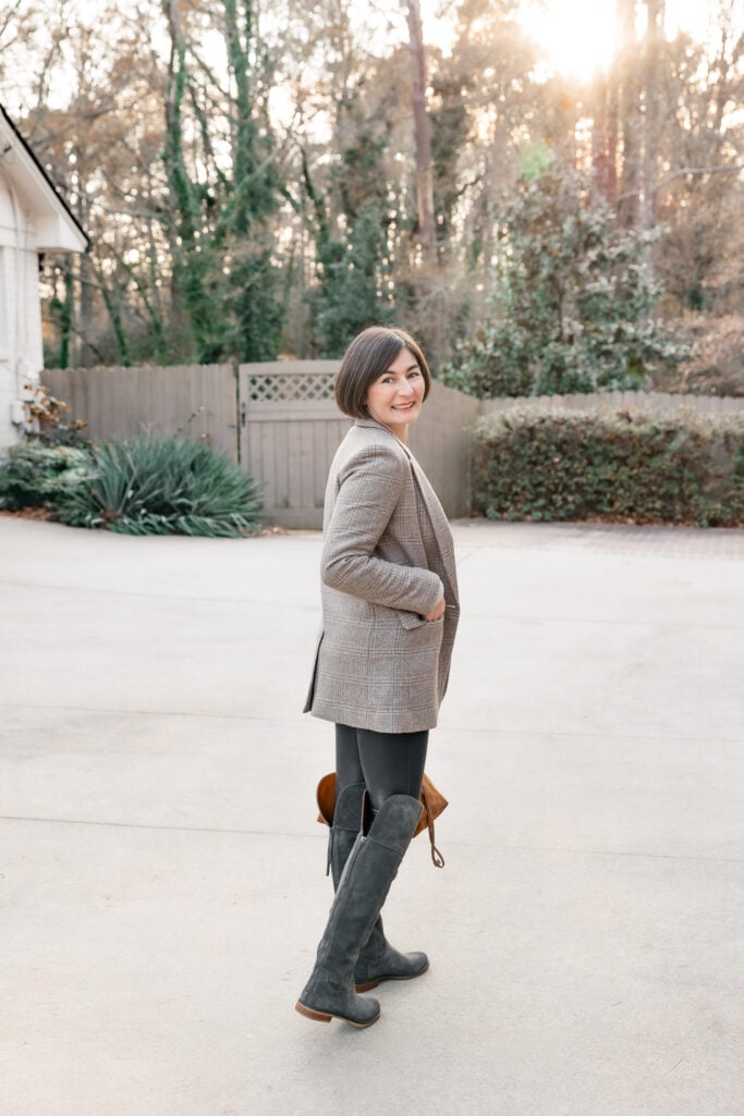 Kelly looking back in petite elevated outfit showing plaid blazer fit with faux leather leggings and tall grey suede boots