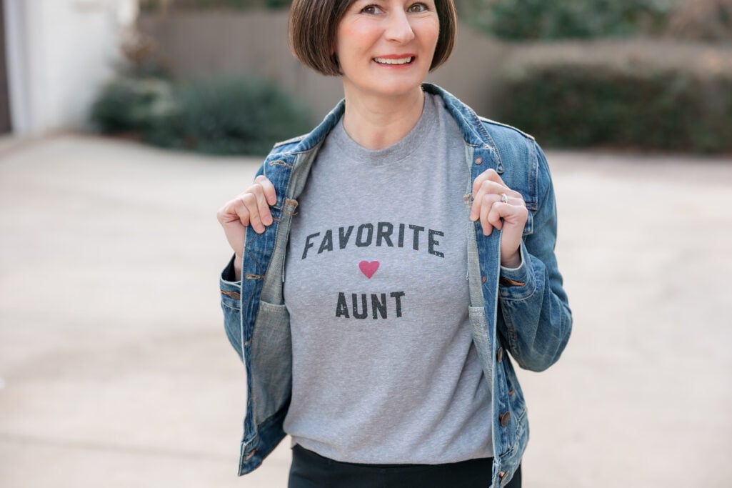 Close-up of Kelly showing gray Favorite Aunt graphic tee with red heart under classic denim jacket - petite casual styling