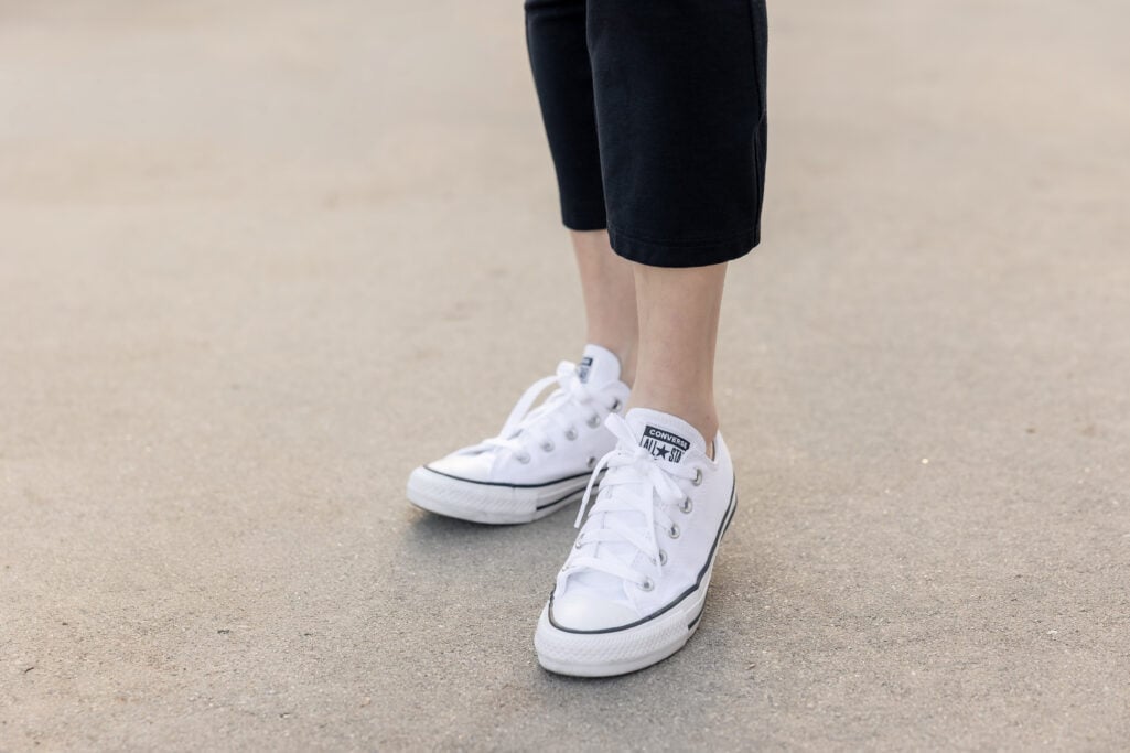 Close up of woman wearing white low-top Converse