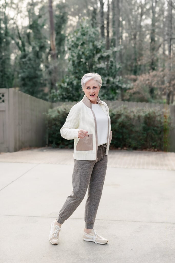 Woman outdoors wearing a cream textured jacket with a white top, gray joggers, and beige-and-white sneakers to avoid outdated style rules.