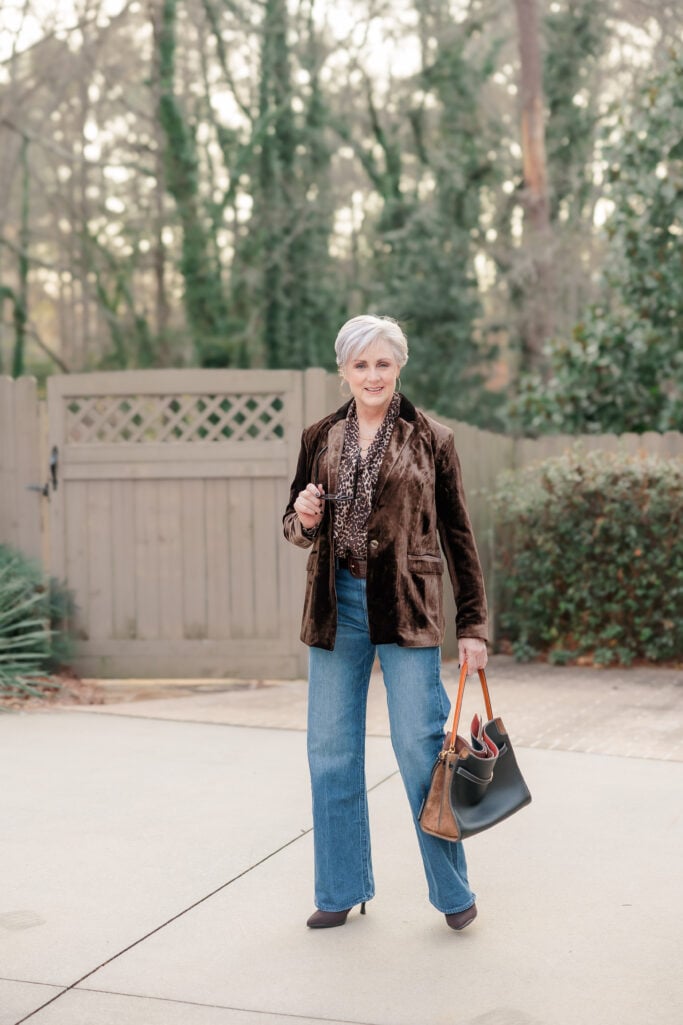  Woman over 50 wearing high-waisted wide leg jeans with cream cashmere sweater and camel blazer