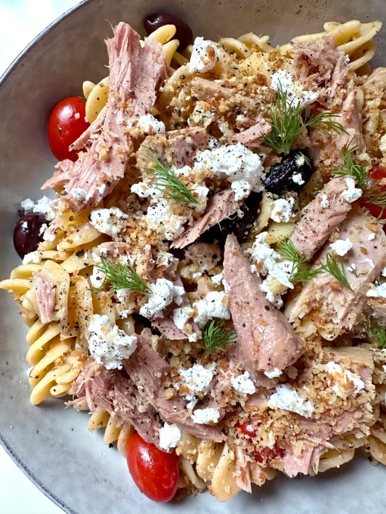 Close-up of Greek pasta showing tuna, feta crumbles, toasted breadcrumbs, and fresh dill