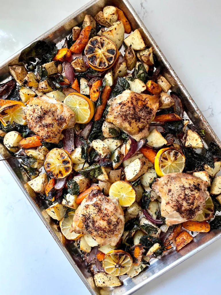 Finished sheet pan chicken fresh from the oven with golden brown chicken thighs, caramelized lemon wheels, and roasted vegetables