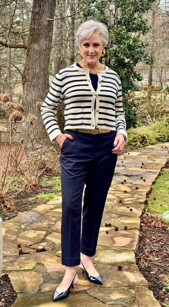 Beth wearing black-and-white striped gold-button cardigan with black trousers and loafers