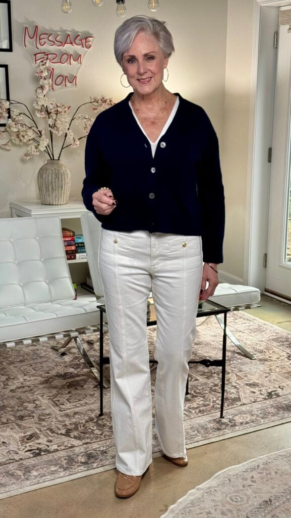 Beth wearing navy v-neck cardigan over white tee with white wide-leg jeans and loafers