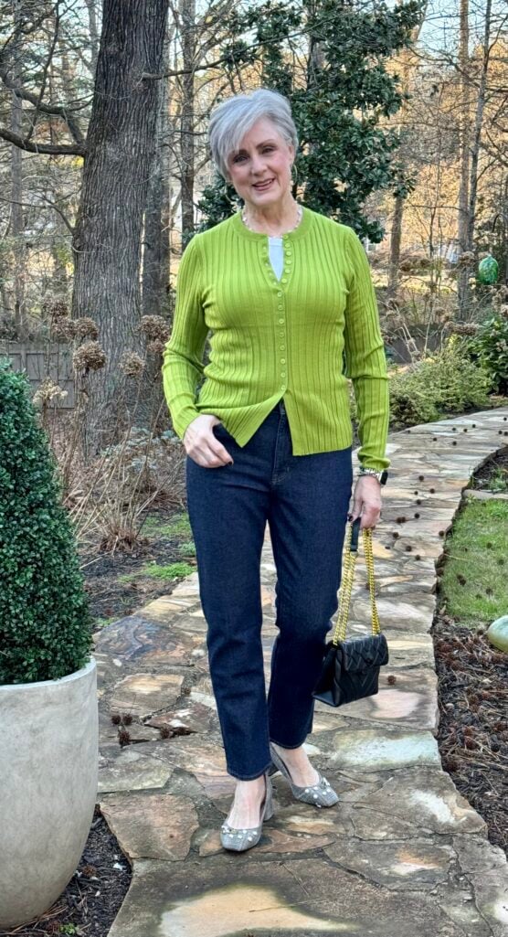 Beth wearing green ribbed cardigan buttoned as a top with dark straight-leg jeans