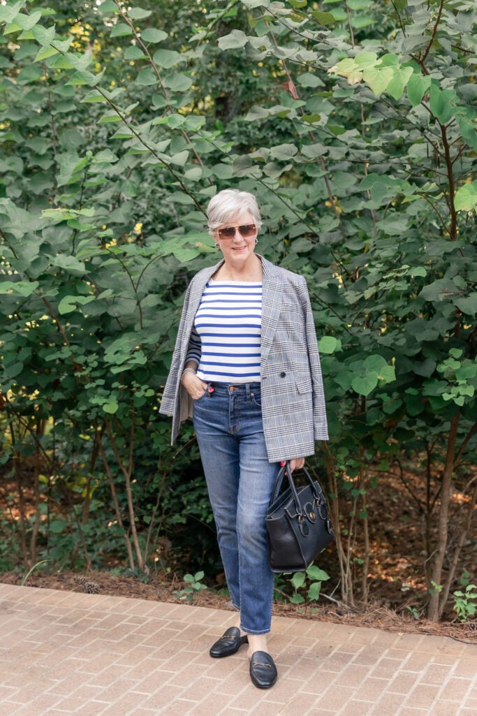 Beth in a gray and blue plaid blazer layered over a blue and white striped tee, styled with slim jeans, black bit mules, and a black leather handbag — how to mix stripes and plaid