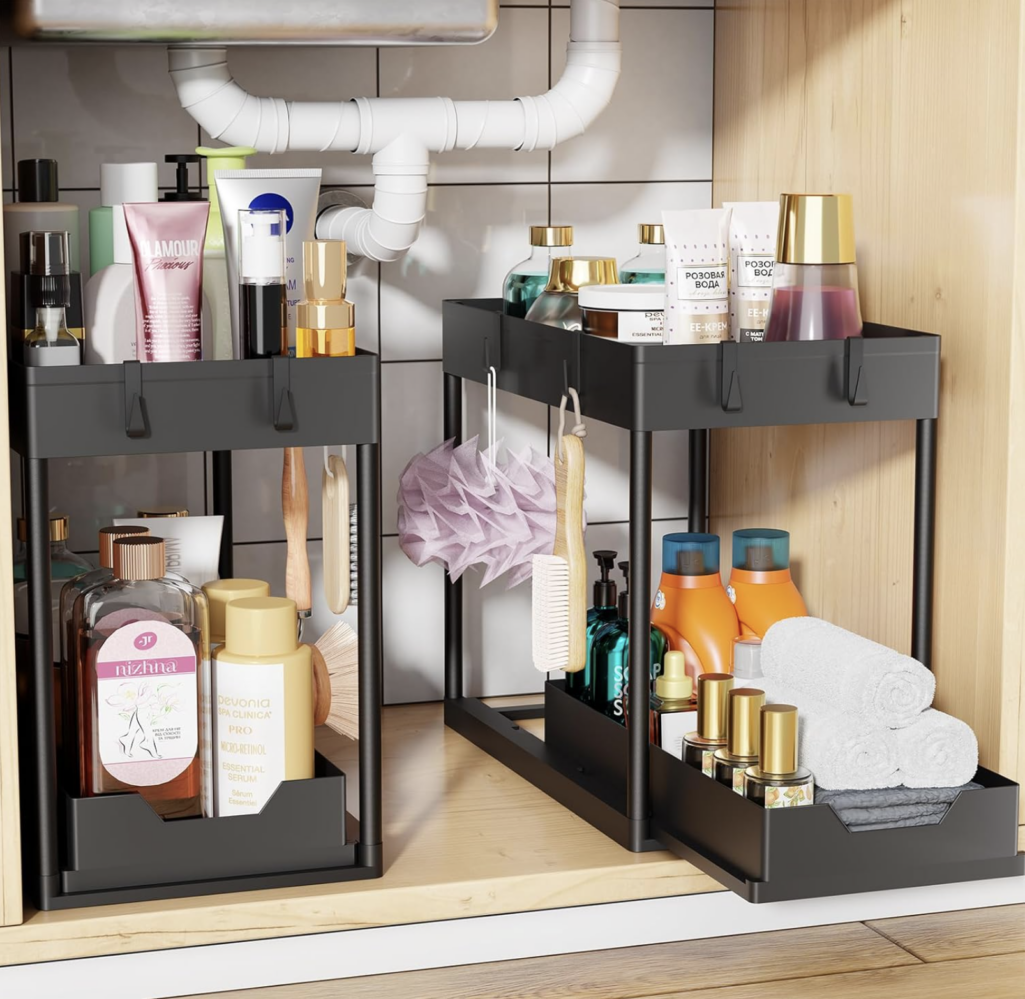 Two-tier under-sink organizer holding cleaning supplies, bottles, and towels, designed to fit around plumbing for efficient storage.