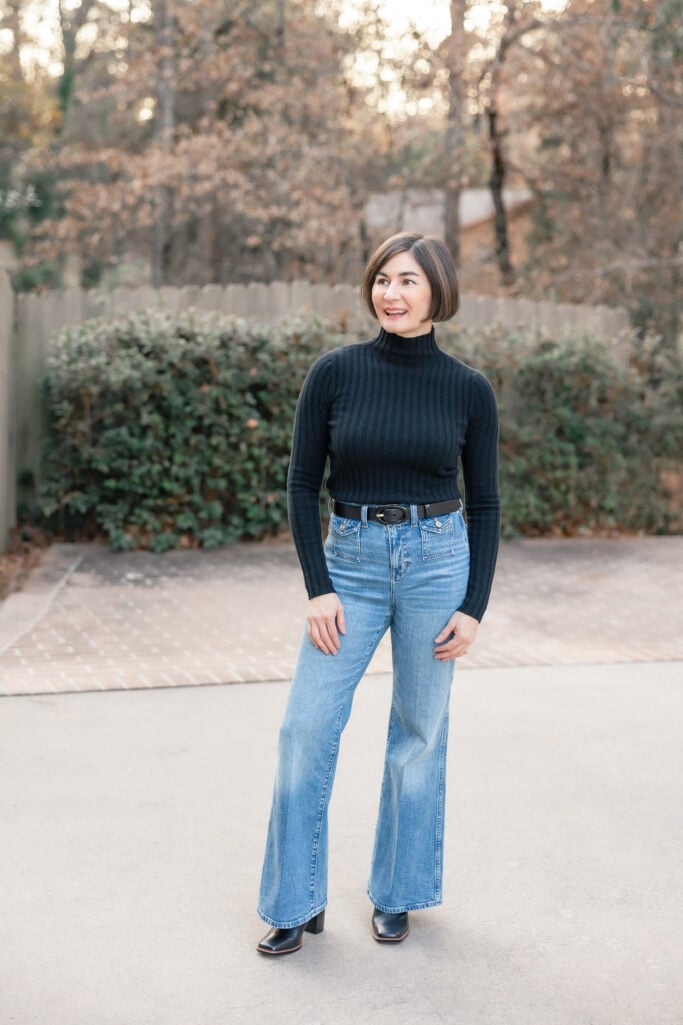 Kelly wearing petite wide leg trouser jeans with black ribbed turtleneck, black belt, and black heeled boots - full length front view showing dramatic wide leg silhouette