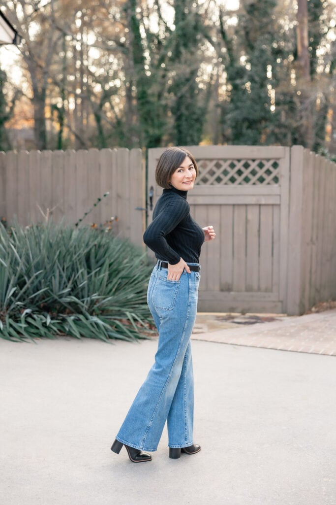 Kelly looking back in petite trouser jeans showing flattering wide leg drape and elongating effect with heeled boots - polished petite denim look
