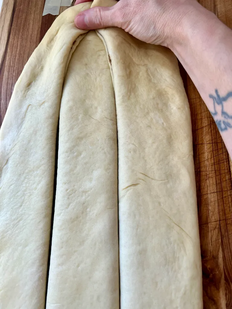 Pressing three strips of filled dough together at the top to begin braiding