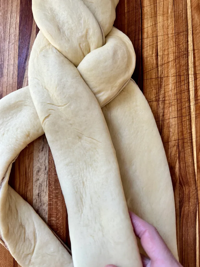 Continuing to braid the filled dough strips, showing the braid pattern forming