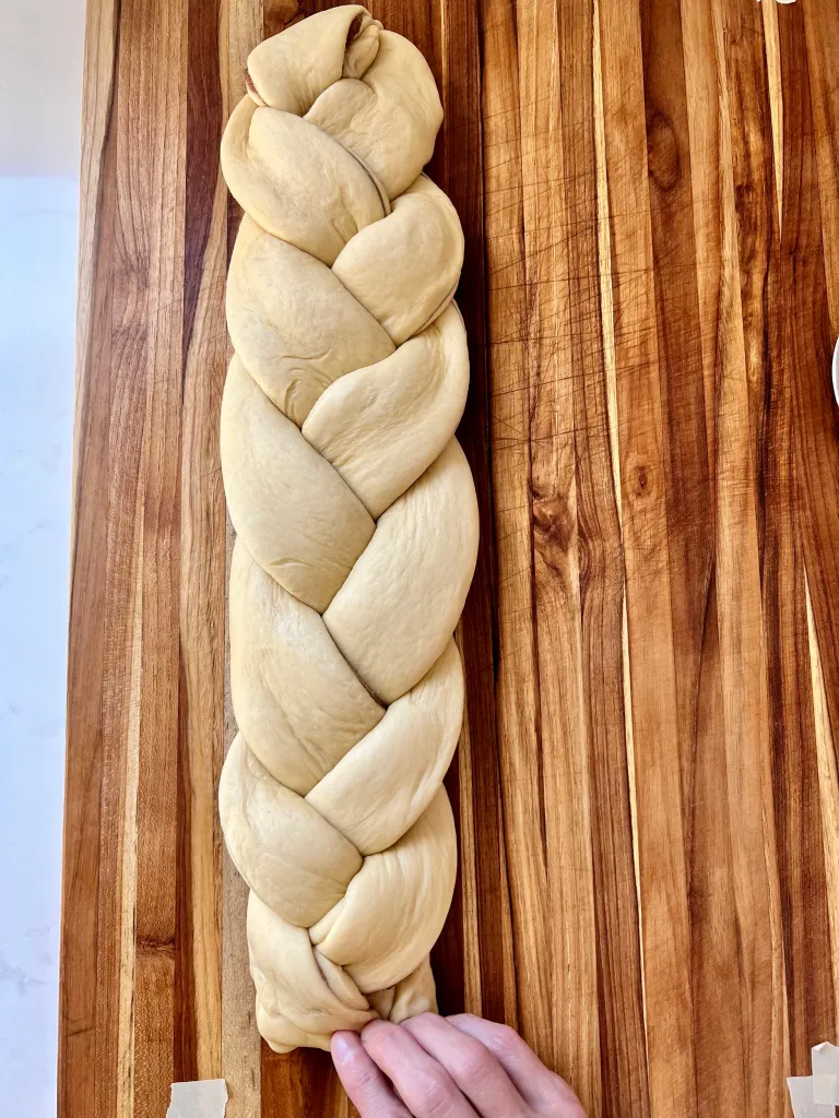 Completed braided dough stretched out on a wooden surface