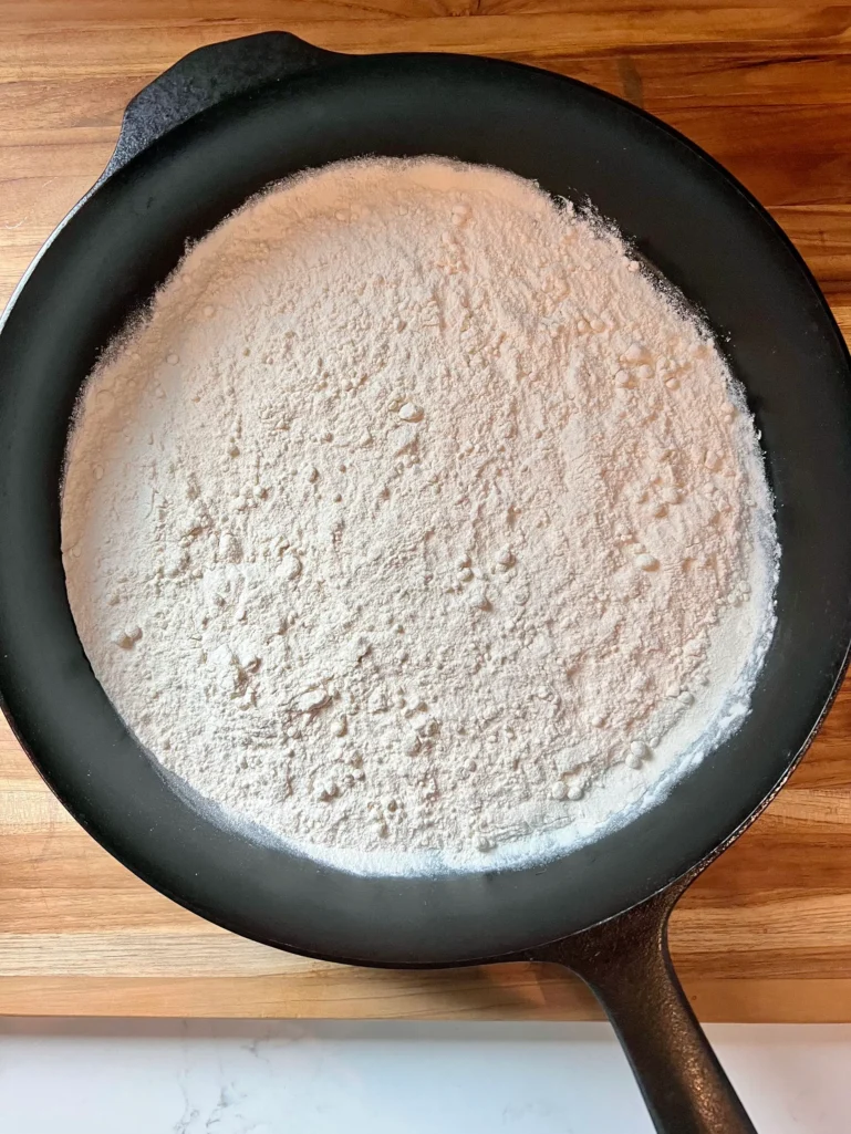 All-purpose flour spread in a cast iron skillet before toasting