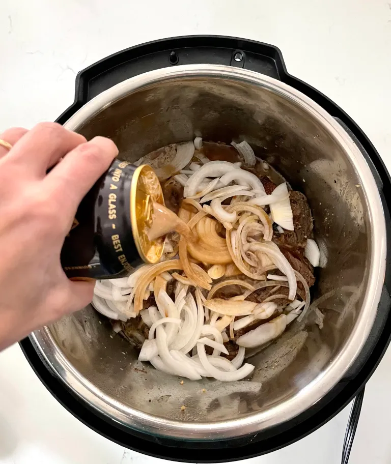 Pouring Guinness over the seared roast and sliced onions in the Instant Pot