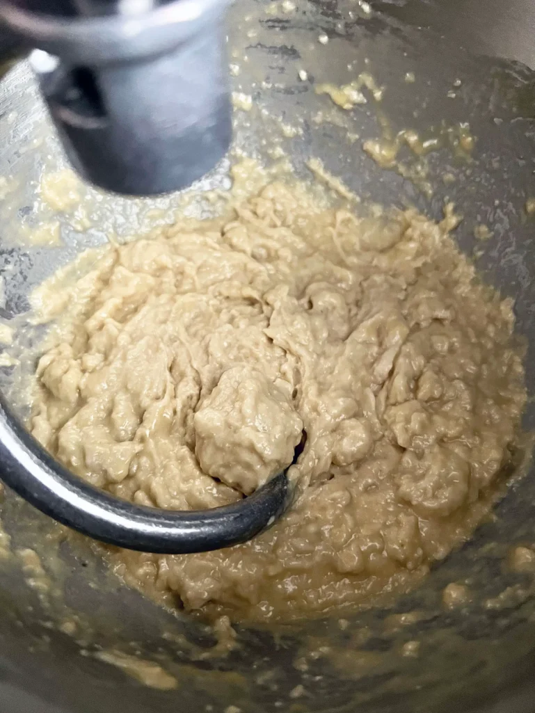 Wet, shaggy brioche dough being mixed with a dough hook in a stand mixer