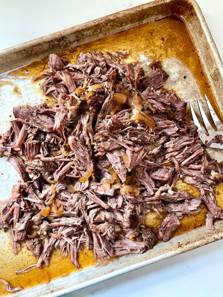 Shredded beef and onions on a sheet pan ready for sandwiches