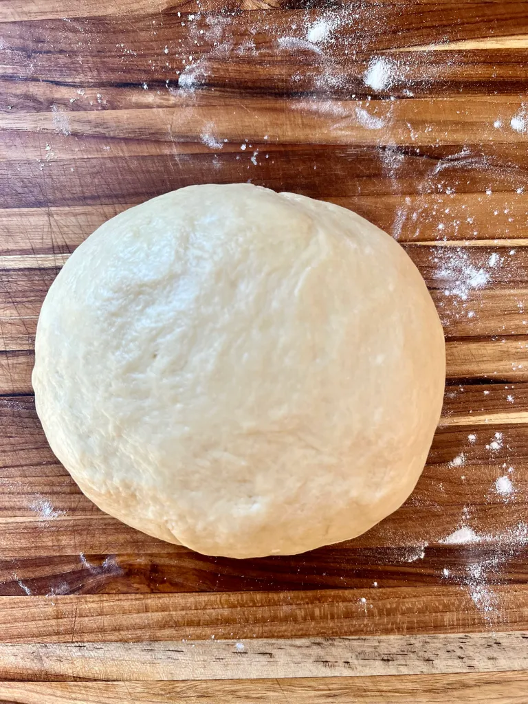 Smooth ball of brioche dough on a floured wooden surface
