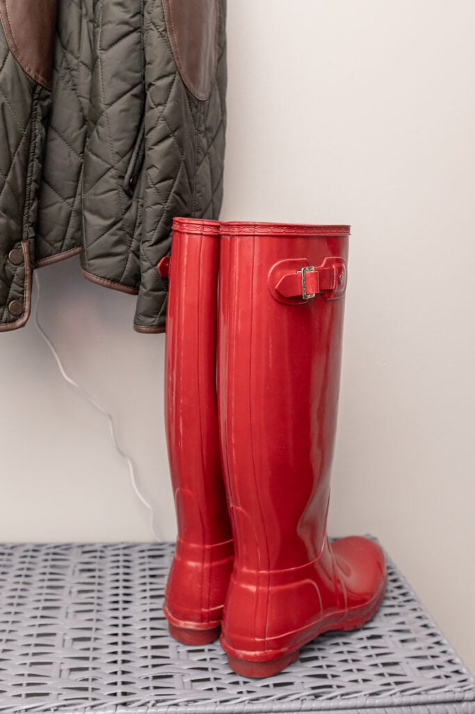 Red glossy Hunter rain boots displayed next to a quilted jacket — red rain boots as a colorful accessory