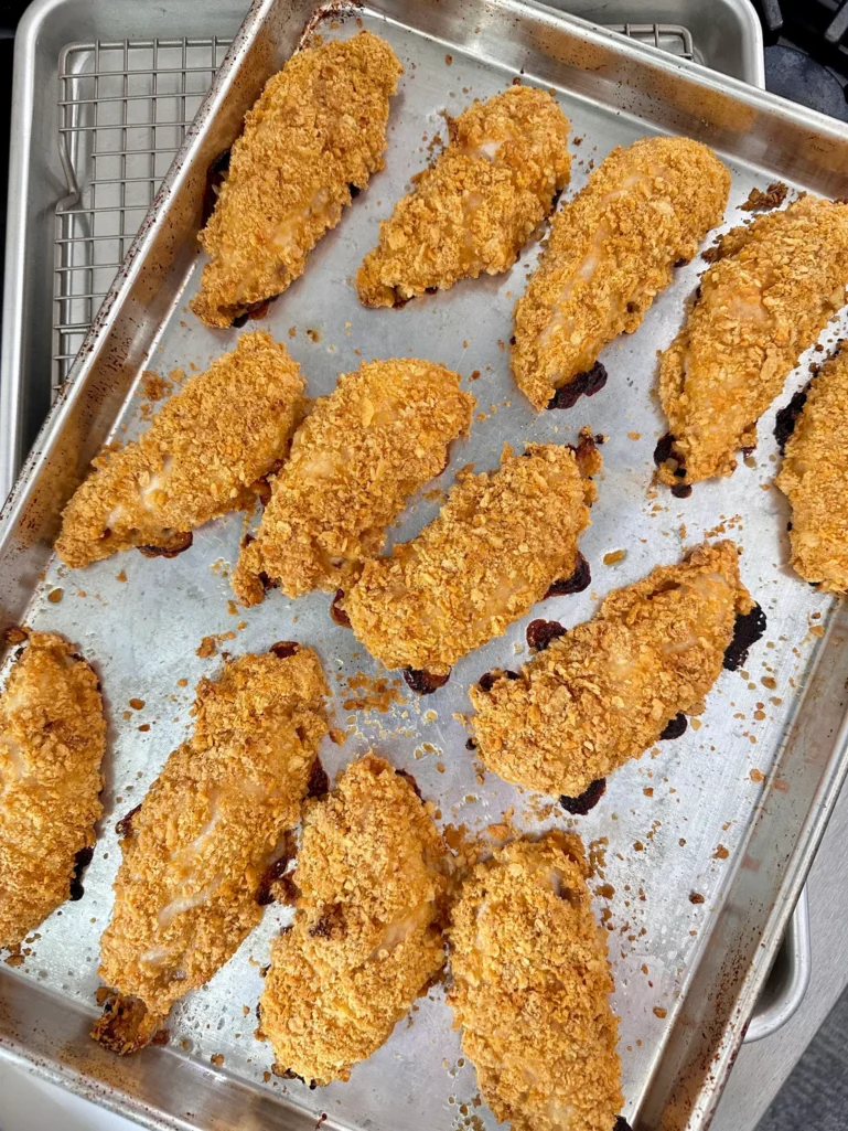 Overhead view of golden baked Cheez-It chicken tenders on a sheet pan fresh from the oven