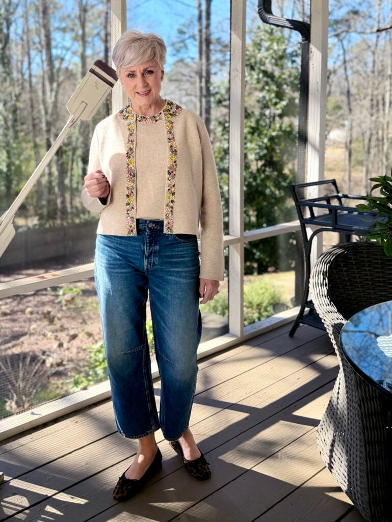 Full-length view of Beth in her embellished cardigan set and barrel leg jeans, showing the relaxed wide silhouette and leopard heels in warm afternoon light