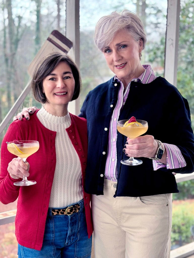 Beth and Kelly raising Raspberry French 75s garnished with fresh raspberries and lemon twists on the screened porch