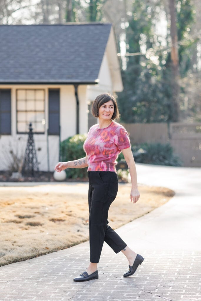 Kelly in a floral sweater tee with black tapered trousers and black loafers — full outfit view