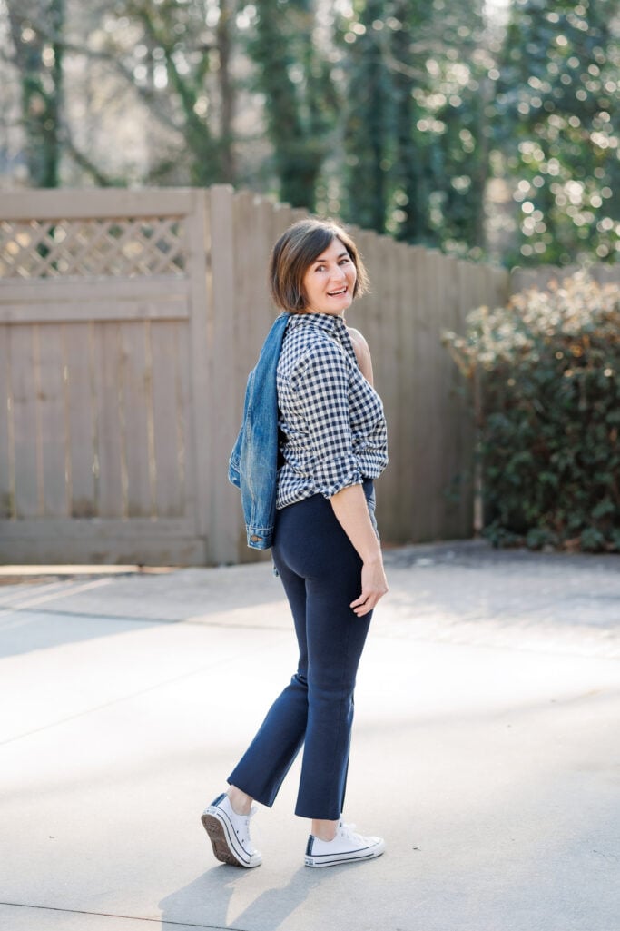 Kelly walking in a gingham shirt and navy kick flare pants — casual petite spring outfit from behind