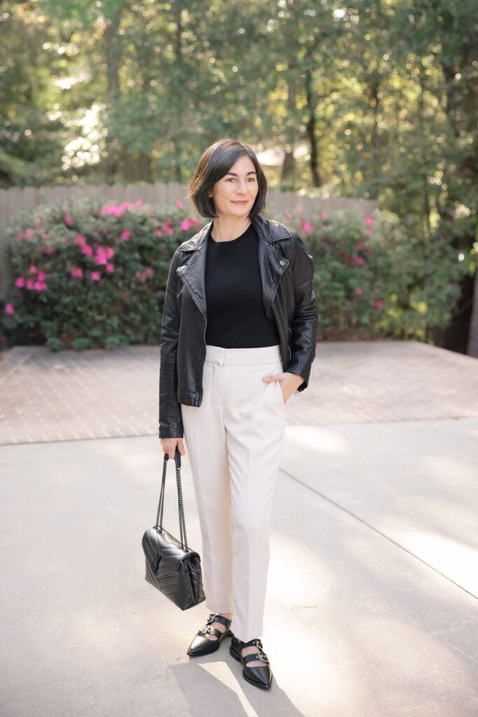 Kelly in a black leather moto jacket over a black cashmere sweater with cream ankle pants and pointed toe mary janes