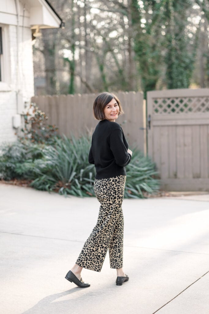 Kelly in a black cashmere sweater with leopard print knit pants and black loafers — leopard as a neutral for petites