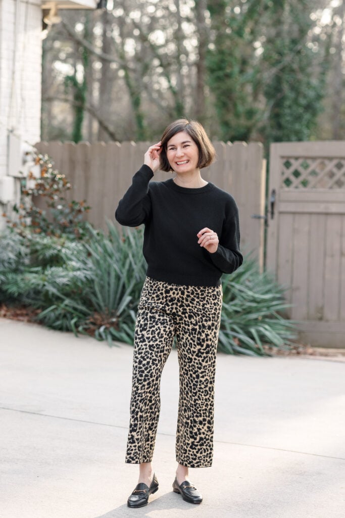 Kelly wearing leopard print pants with a black sweater and loafers — front view of a classic petite outfit