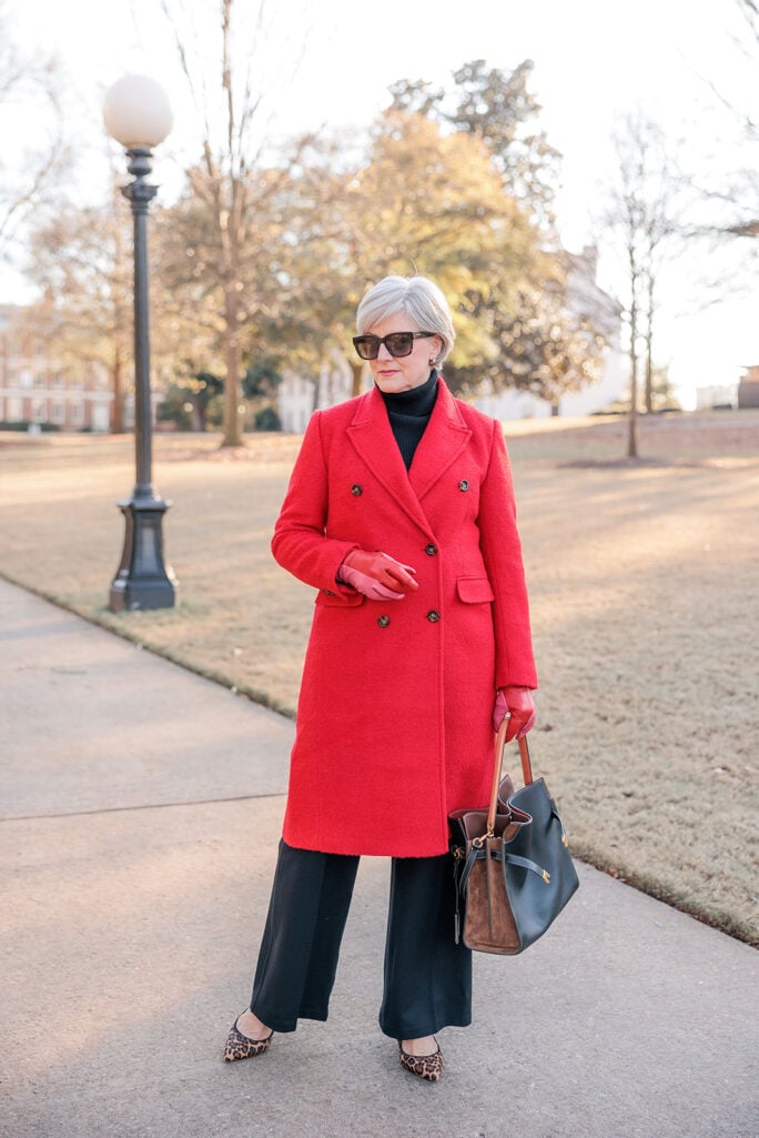 Beth wearing a long red wool overcoat over a black turtleneck and black wide-leg pants, with leopard pumps and red leather gloves — chic red overcoat outfit for women over 50