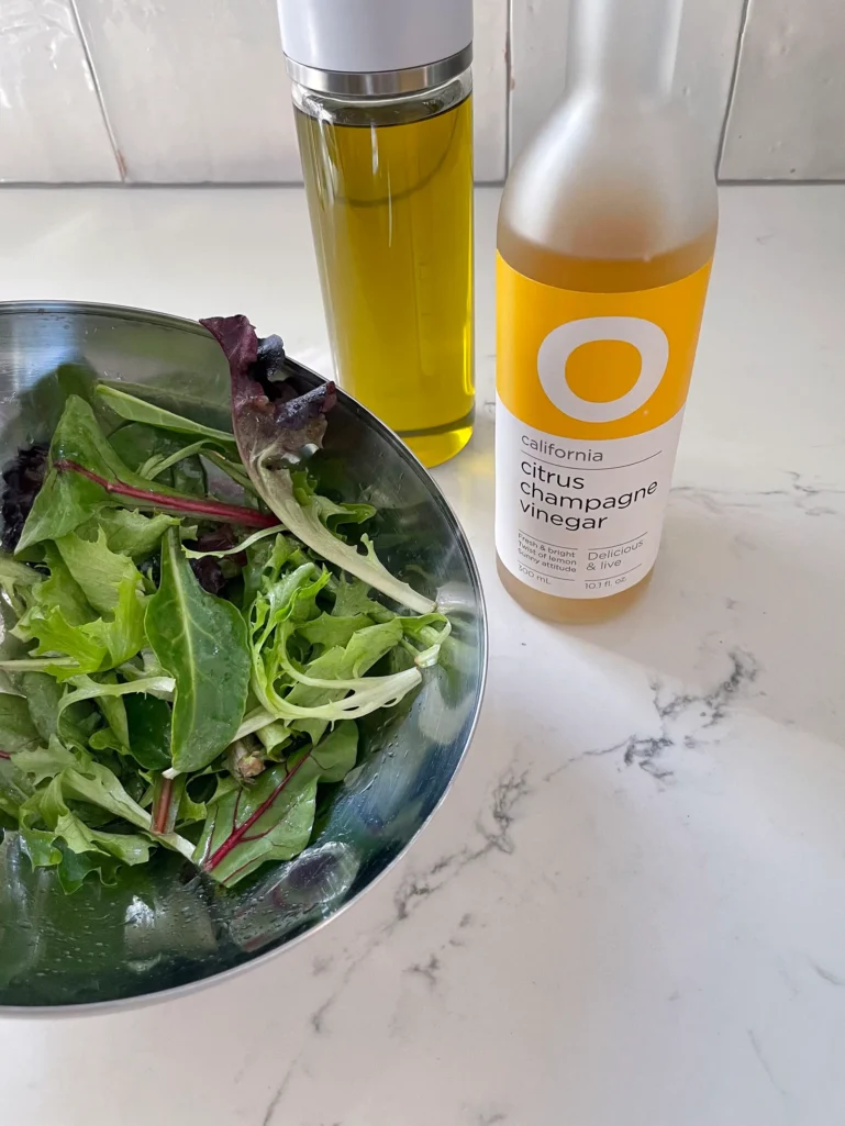 Bowl of spring greens with olive oil and citrus champagne vinegar for the side salad