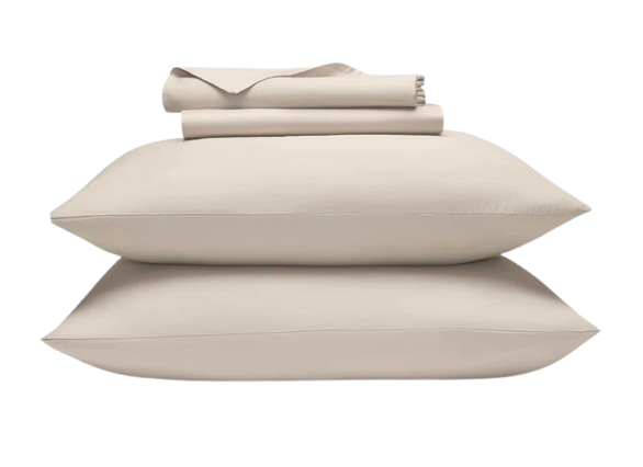 Cream-colored Brooklinen Luxe Sateen sheets neatly folded on a bed, showcasing smooth, wrinkle-resistant fabric with a subtle sheen.