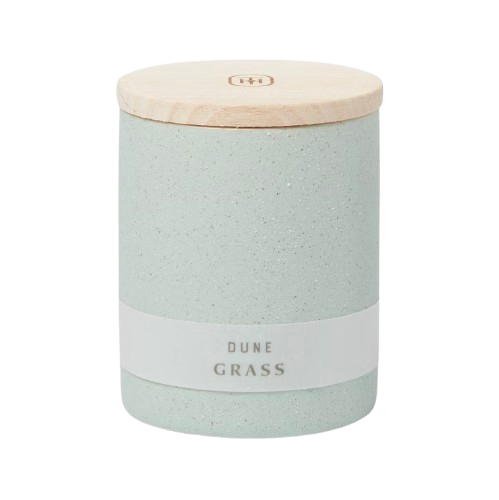 Matte pale seafoam green candle labeled “Dune Grass” with a smooth wooden lid and minimalist neutral packaging.
