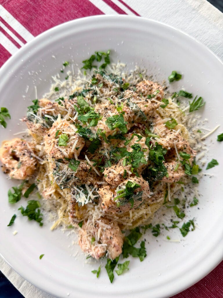 Overhead view of Creamy Garlic Butter Shrimp over spaghetti, garnished generously with parmesan and fresh parsley on a white plate