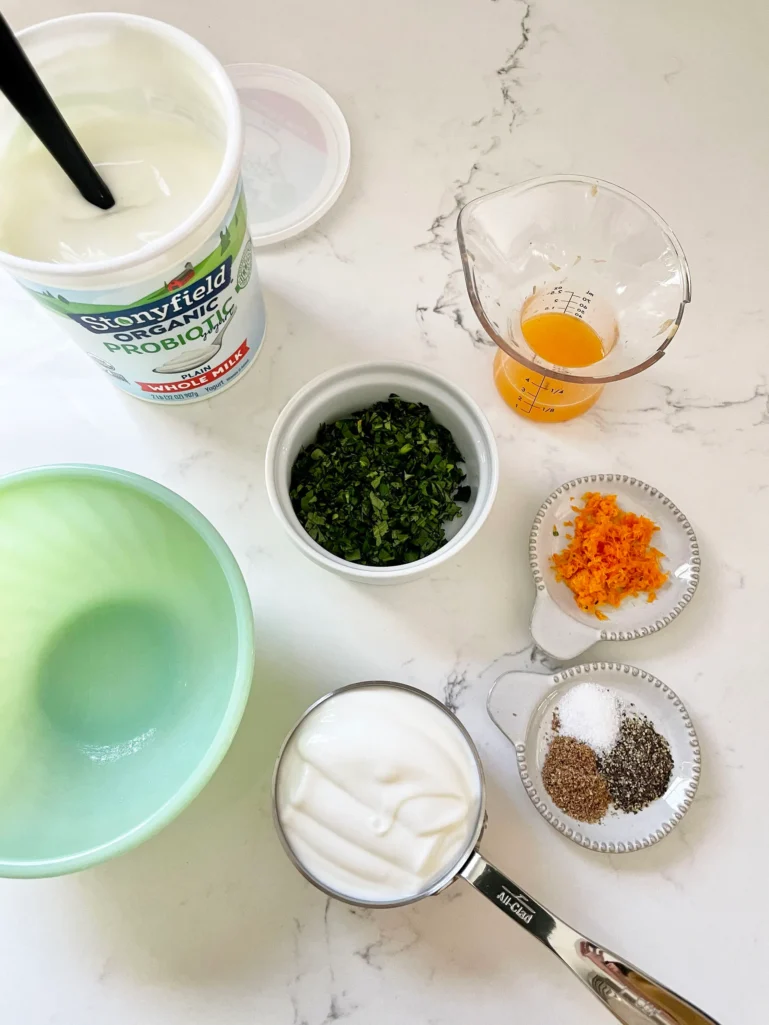 Yogurt sauce ingredients laid out: Stonyfield whole milk yogurt, chopped cilantro, orange juice, orange zest, and spices