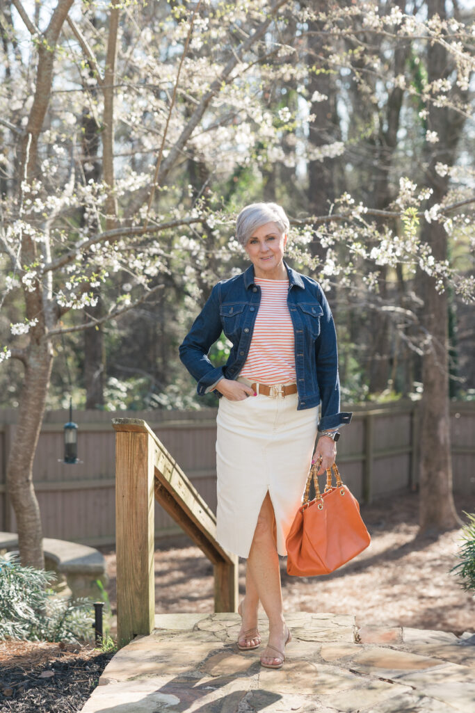 White denim split-front skirt + orange stripe tee + denim jacket + orange bamboo-handle bag + tan sandals