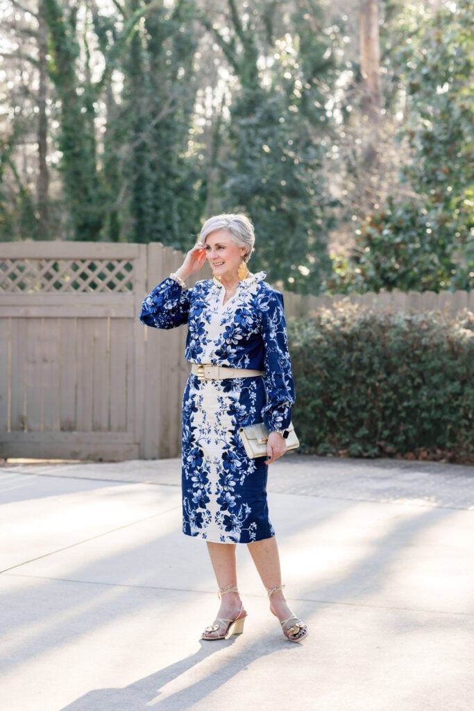 bold floral pattern for women over 50 — navy floral dress styled with gold