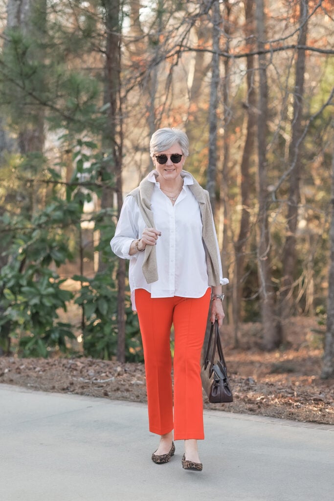 bold color for women over 50 — tomato red trousers styled with white shirt