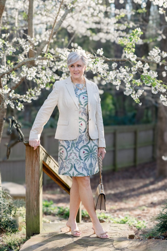 Beth Djalali wearing a tropical-print shift dress with cream blazer and Tory Burch bag — an elegant easter dress option for women over 50
