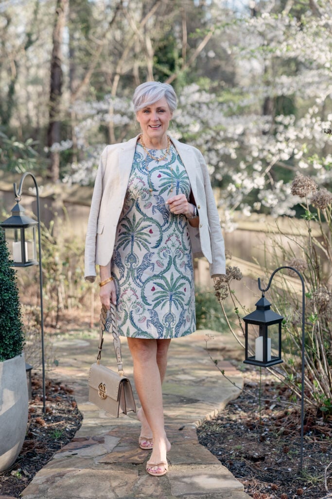 Beth Djalali wearing a tropical-print shift dress with cream blazer and Tory Burch bag — an elegant easter dress option for women over 50