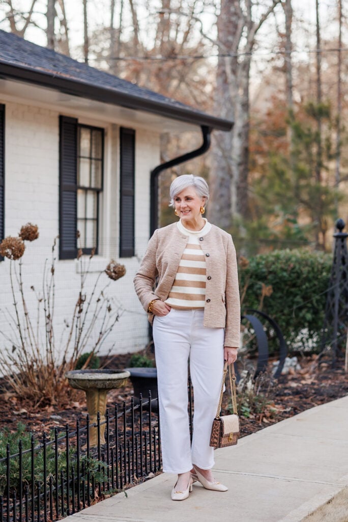 Tan cropped jacket over striped top with white jeans and neutral flats.