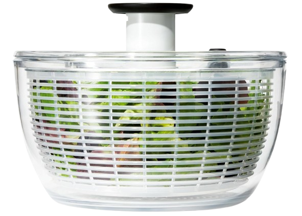 Clear OXO Good Grips salad spinner with white inner basket and black pump handle, shown filled with leafy greens for washing and drying lettuce and salad mixes.