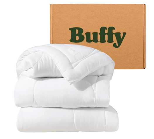Buffy Cloud queen comforter in bright white, featuring a fluffy, quilted design with soft, lightweight fill, styled folded in front of branded packaging box.