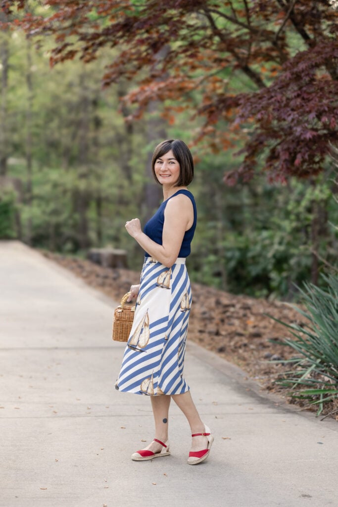 Kelly in full-length nautical outfit featuring Ralph Lauren button front crepe midi skirt, navy ribbed knit top, red espadrille flats and wicker bag — petite nautical spring styling