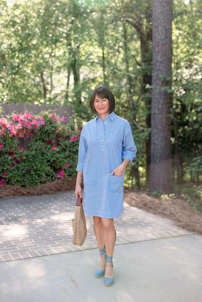 Kelly in blue and white striped shirtdress with blue lace-up espadrille wedges and natural straw bag, azalea backdrop — shirtdress for petites spring outfit